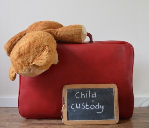 a stuffed animal on top of a suitcase with a chalkboard sign in front of it that says child custody